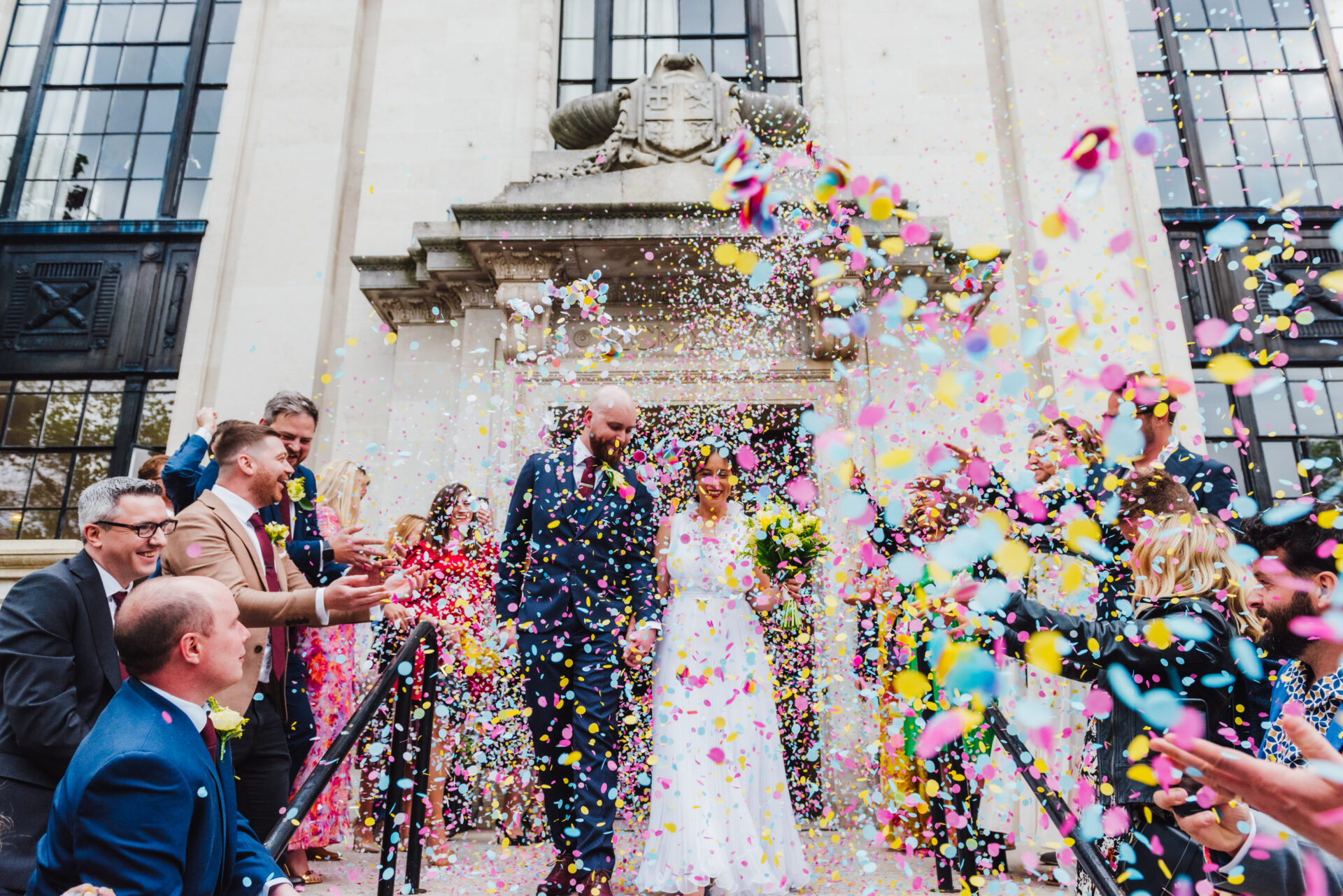 Newly Married couple leaving Islington town hall London in a flurry of rainbow coloured confetti