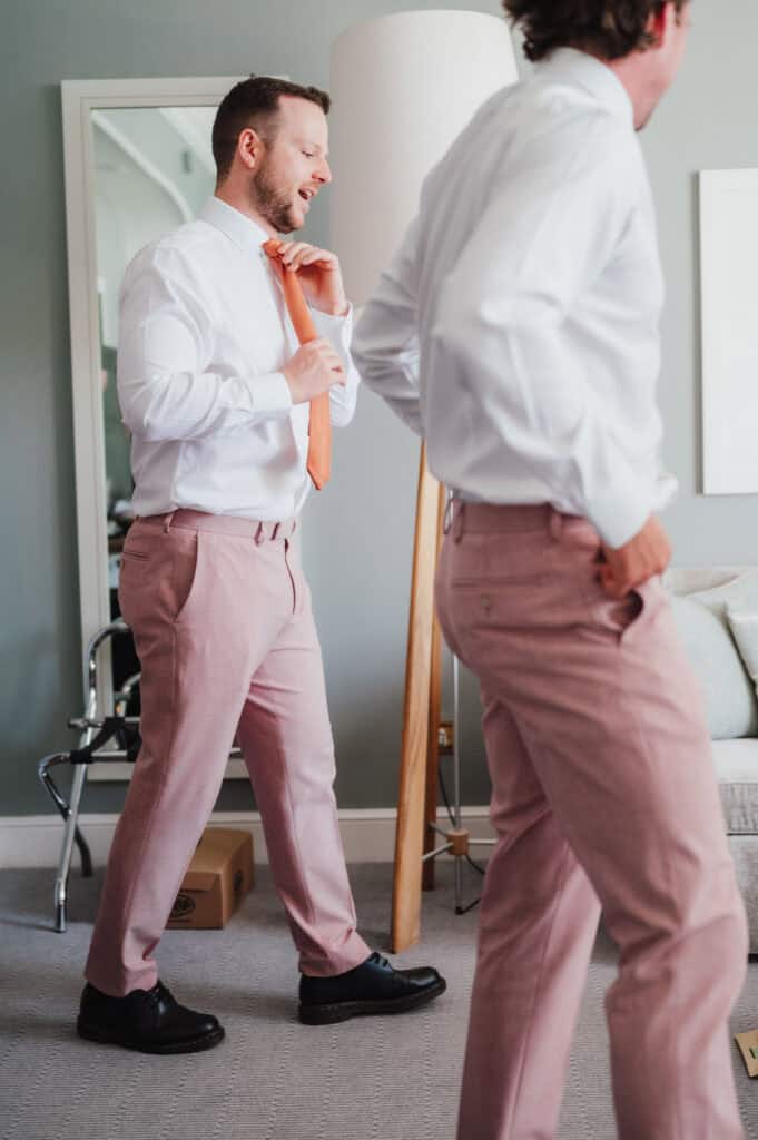 Clear image of stylish groom getting ready with a tie in a modern bedroom.
