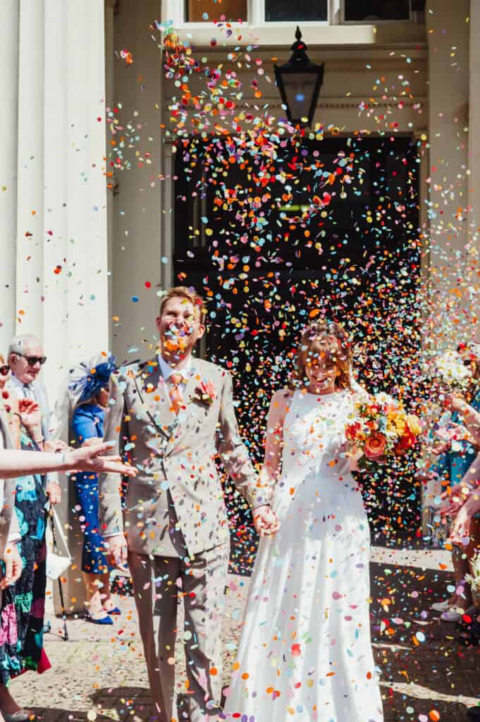 Vibrant wedding scene with confetti, bride and groom cheerful, colourful rainbow coloured confetti at Brighton Town Hall