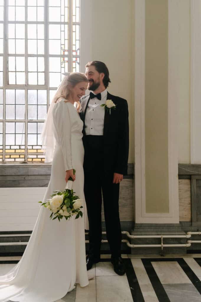 Bridal bride and groom smiling in church, wedding attire, genuine joy, romantic moment.