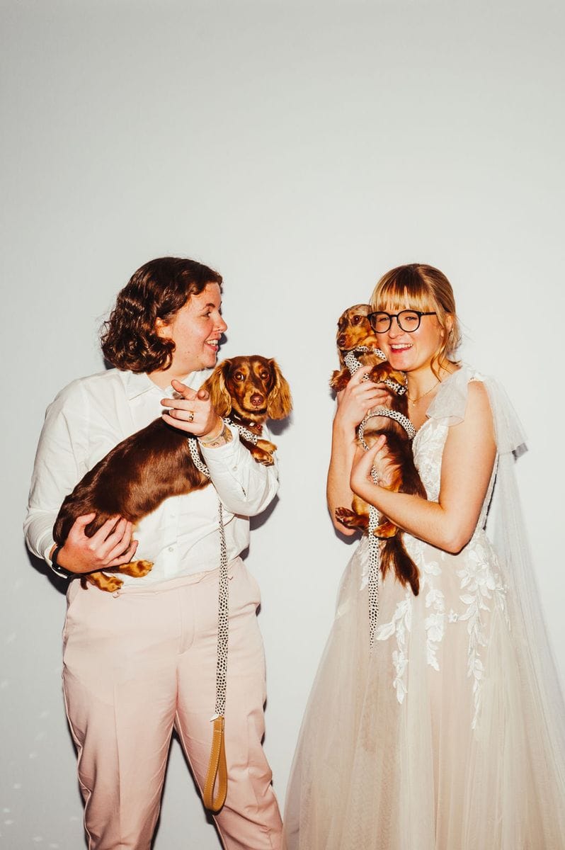 Two brides holding dachshunds laughing