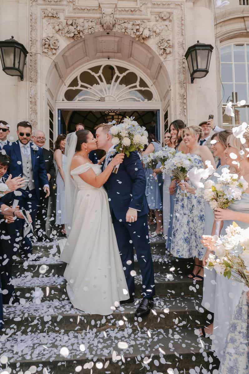 Couple kissing on town hall steps with confetti