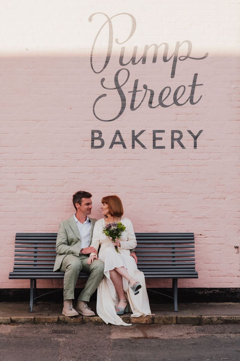 Couple sitting on a bench outside Pump Street Bakery, relaxed wedding portrait by Sidey Clark