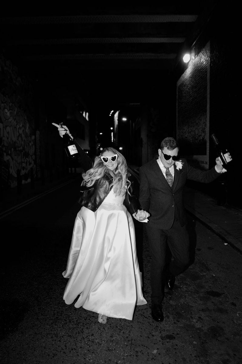 Couple running through tunnel with champagne
