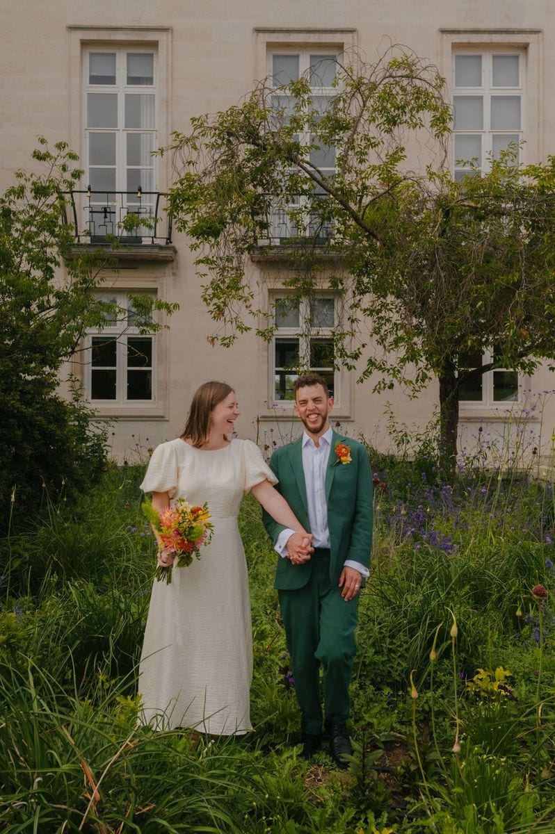 Laughing couple in a wildflower garden outside Waltham Forest Town Hall, summer wedding by Sidey Clark